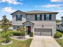 Charming two-story home boasts a gray exterior, manicured landscaping, and an attached two-car garage at 8226 Summer Brook Ct, Land O Lakes, FL 34638