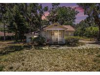 Charming single-story home featuring a cozy front porch surrounded by lush landscaping and mature trees at 11101 Corlett Rd, Riverview, FL 33578