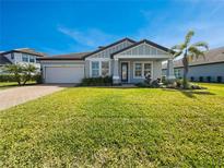 Charming single-story home boasts a well-manicured lawn, mature palm tree, and a two-car garage at 11443 Apple Tree Cir, Bradenton, FL 34211