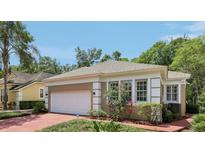 Side view of single-story home featuring a white garage door, brick driveway and well-maintained landscaping at 15324 Sherwood Forest Dr, Tampa, FL 33647