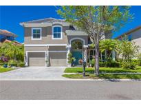Charming two-story home featuring a well-manicured lawn, lush landscaping, and a welcoming turquoise-colored front door at 2305 Messenger Cir, Safety Harbor, FL 34695