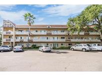Multi-level condo complex with ample parking, mature trees, and well-maintained facade under a sunny sky at 2310 Denmark St # 30, Clearwater, FL 33763