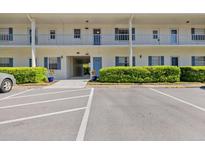 Two-story condo building with blue shutters, landscaping, and assigned parking at 500 Glennes Ln # 205, Dunedin, FL 34698