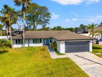 Charming single-story home with a two-car garage, blue front door, and beautifully landscaped front yard at 6070 Denver Ne St, St Petersburg, FL 33703