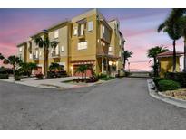 Stunning yellow townhome with a red tile roof, lush tropical landscaping, and a secure gated entrance at 6412 Mayra Shores Ln, Apollo Beach, FL 33572