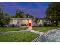 Charming single-story home featuring a vibrant red door and freshly manicured green lawn at 7000 14Th N St, St Petersburg, FL 33702