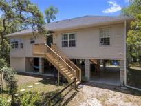 Charming raised home featuring wood stairs, neutral siding, and spacious ground-level covered parking and recreational area at 9019 Stone Dr, Webster, FL 33597