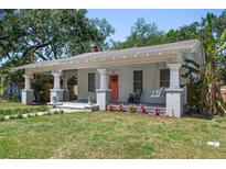 Inviting single-story home with a covered porch, porch swing and vibrant landscaping at 906 E Patterson St, Tampa, FL 33604
