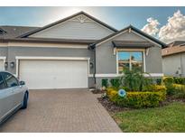 Charming single-story home with a two-car garage, brick driveway, and attractive landscaping at 9943 Campanula Ct, Land O Lakes, FL 34637