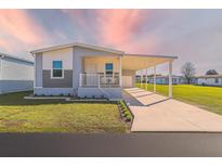 Inviting single-story home with a covered carport and a well-manicured lawn with beautiful sunset at 10029 Wellington Ave, Dade City, FL 33525