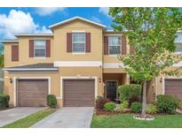 Inviting townhome featuring a well-maintained lawn, a two-car garage, and charming curb appeal at 12913 Dream Catcher Way, Riverview, FL 33579
