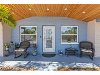 Inviting front porch with comfortable seating, two windows and charming decor at 1344 Dartmouth Dr, Holiday, FL 34691
