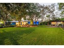 Expansive green lawn view featuring a charming home and inviting outdoor seating area amid mature trees at 1880 Belleair Rd, Clearwater, FL 33764