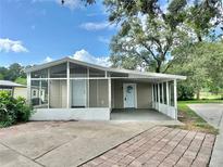 Charming home featuring a screened-in porch and covered carport, perfect for enjoying the outdoors at 34141 Tree Lake Dr, Wesley Chapel, FL 33543