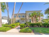 Two-story home featuring manicured landscaping, palm trees and a second story balcony on a sunny day at 4301 W Swann Ave, Tampa, FL 33609