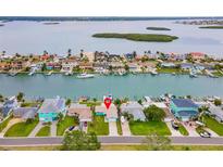 Aerial view of waterfront homes, with boat docks, and a coastal community in the background at 525 Lillian Dr, Madeira Beach, FL 33708