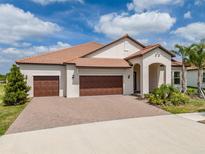 Charming single-story home featuring a tile roof, three-car garage, and inviting front yard with manicured landscaping at 5329 Windy Grove Dr, Wimauma, FL 33598