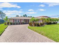 Charming home featuring a brick driveway, lush landscaping, and well-maintained lawn at 6790 Burning Tree Dr, Seminole, FL 33777
