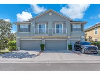 Two-story townhome featuring gray exterior, a pair of balconies, three garage doors, and well-maintained landscaping at 6851 Breezy Palm Dr, Riverview, FL 33578