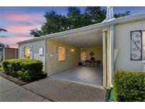 Charming home featuring a covered carport with seating and manicured landscaping, offering a warm and inviting curb appeal at 854 Sky Loch N Dr, Dunedin, FL 34698