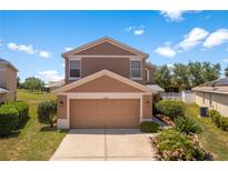 Two-story home with a two car garage and landscaped front yard on a sunny day at 11449 Crestlake Village Dr, Riverview, FL 33569