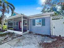 Exterior view of screened in porch, blue shutters, and white fenced yard at 1214 Bay Shore Blvd, Indian Rocks Beach, FL 33785