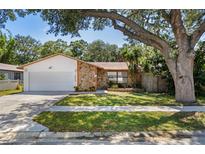 Charming single-Gathering home featuring stone accents, a well-manicured lawn, and mature shade trees at 1628 12Th Sw St, Largo, FL 33778