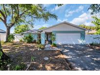 Charming single-story home featuring a manicured lawn, mature tree, and a two-car garage at 2366 Covington Dr, Clearwater, FL 33763