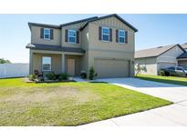 Two-story home featuring a well-kept lawn, two-car garage, and neutral-toned exterior at 35853 Buttonweed Trl, Zephyrhills, FL 33541