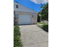 Home exterior with white garage door, number 414, and cracked driveway lined with manicured greenery at 414 Danube Ave, Tampa, FL 33606