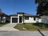 Charming single-story home featuring a black garage door and well-maintained landscaping at 7208 N Glen Ave, Tampa, FL 33614
