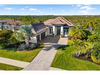 Beautifully landscaped home with a brick driveway and lush green lawn at 11506 Harbourside Ln, Parrish, FL 34219