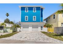 Bright blue two-story home featuring a large driveway, two-car garage and white trim at 13117 4Th E St, Madeira Beach, FL 33708