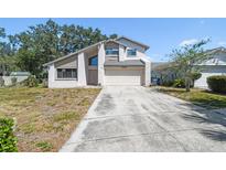Two story home featuring a large driveway, attached garage, white exterior, and well-maintained yard at 16169 Gardendale Dr, Tampa, FL 33624