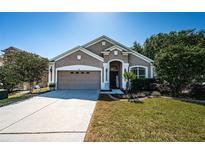 Charming single-story home with a well-manicured lawn and attached two-car garage on a sunny day at 19610 Sunset Bay Dr, Land O Lakes, FL 34638
