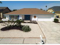 Charming single-story home boasts a well-maintained yard with decorative landscaping and a two-car garage at 6528 Santiago Ct, Apollo Beach, FL 33572