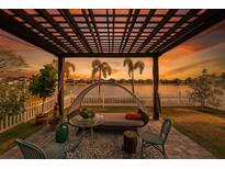 Backyard patio with lounge seating overlooks picturesque water view and tropical landscaping at sunset at 13622 Tonya Anne Dr, Riverview, FL 33579