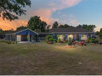 Charming single-story home with beautiful landscaping, including colorful flower beds and a spacious front yard at 14721 Scharber Rd, Dade City, FL 33525