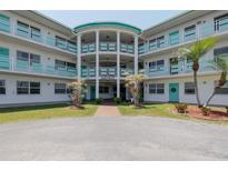 Beautiful condo building with lovely landscaping, light blue railings, and a light-filled entryway at 1950 59Th N Ave # 208, St Petersburg, FL 33714