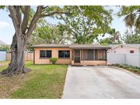 Charming single-story home featuring a large tree and screened front porch at 7141 56Th N St, Pinellas Park, FL 33781