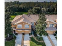 Aerial view of a tan townhome complex featuring attached garages, manicured landscaping and mature trees at 11833 Castine St, New Port Richey, FL 34654