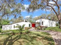 Stunning modern home with a red front door, angled roofs, and lush landscaping at 2947 Cedar Trce, Tarpon Springs, FL 34688