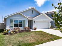 Charming single-Gathering home featuring manicured lawn, two-car garage, light gray exterior and pleasant landscaping at 5166 Plumeria Dr, Wimauma, FL 33598