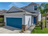 Charming two-story home featuring a bright blue garage door, stone accents, and well-manicured lawn at 6222 Trent Creek Dr, Sun City Center, FL 33573