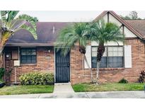 Charming single-story brick home with a black steel door, well-maintained lawn, and picturesque palm trees at 6307 Morning Sun Pl, Tampa, FL 33614