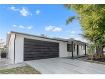 Charming single-story home featuring a stylish black garage door and well-maintained front yard at 9135 Suffolk Ln, Port Richey, FL 34668