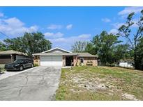 Front exterior of single Gathering home with two car garage and long driveway at 1399 Leeward Ave, Spring Hill, FL 34606