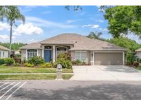 Charming single-story home featuring manicured landscaping, neutral paint, and an attached two-car garage at 18714 Chemille Dr, Lutz, FL 33558