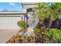 Charming home with a well-maintained lawn and colorful garden beds, showcasing its welcoming curb appeal at 20203 Merry Oak Ave, Tampa, FL 33647