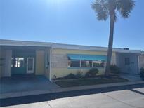 Charming single-story home with yellow paint, turquoise awning, and mature palm tree at 250 Rosery Nw Rd # 295, Largo, FL 33770